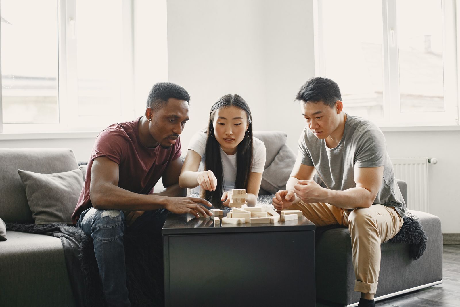 Friends playing a stacking block game in a living room