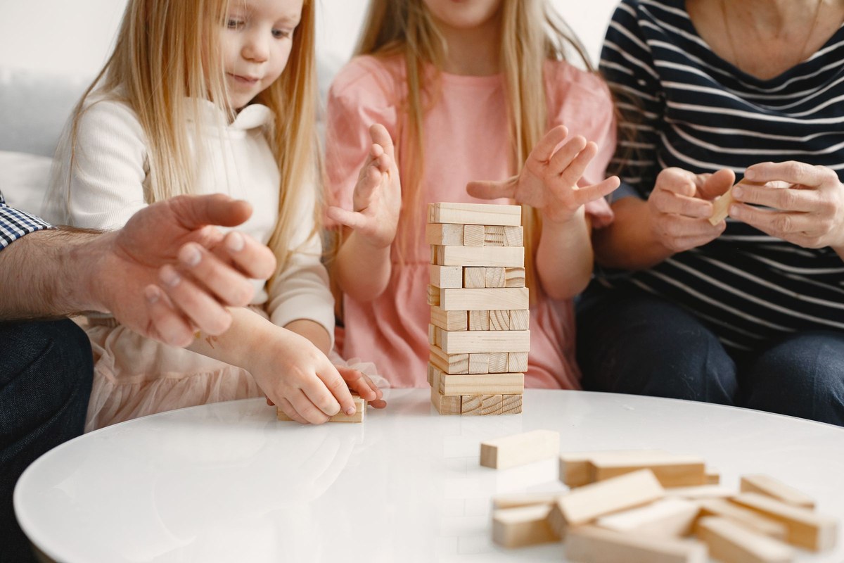 A family steadying a wobbling wooden block tower during a game