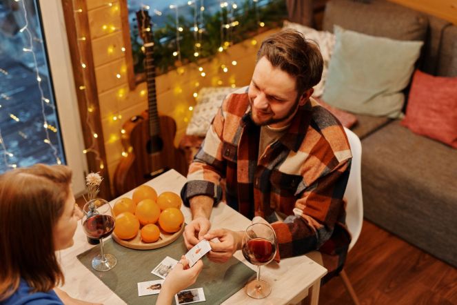 A cozy at-home date night with wine, a card game, and string lights