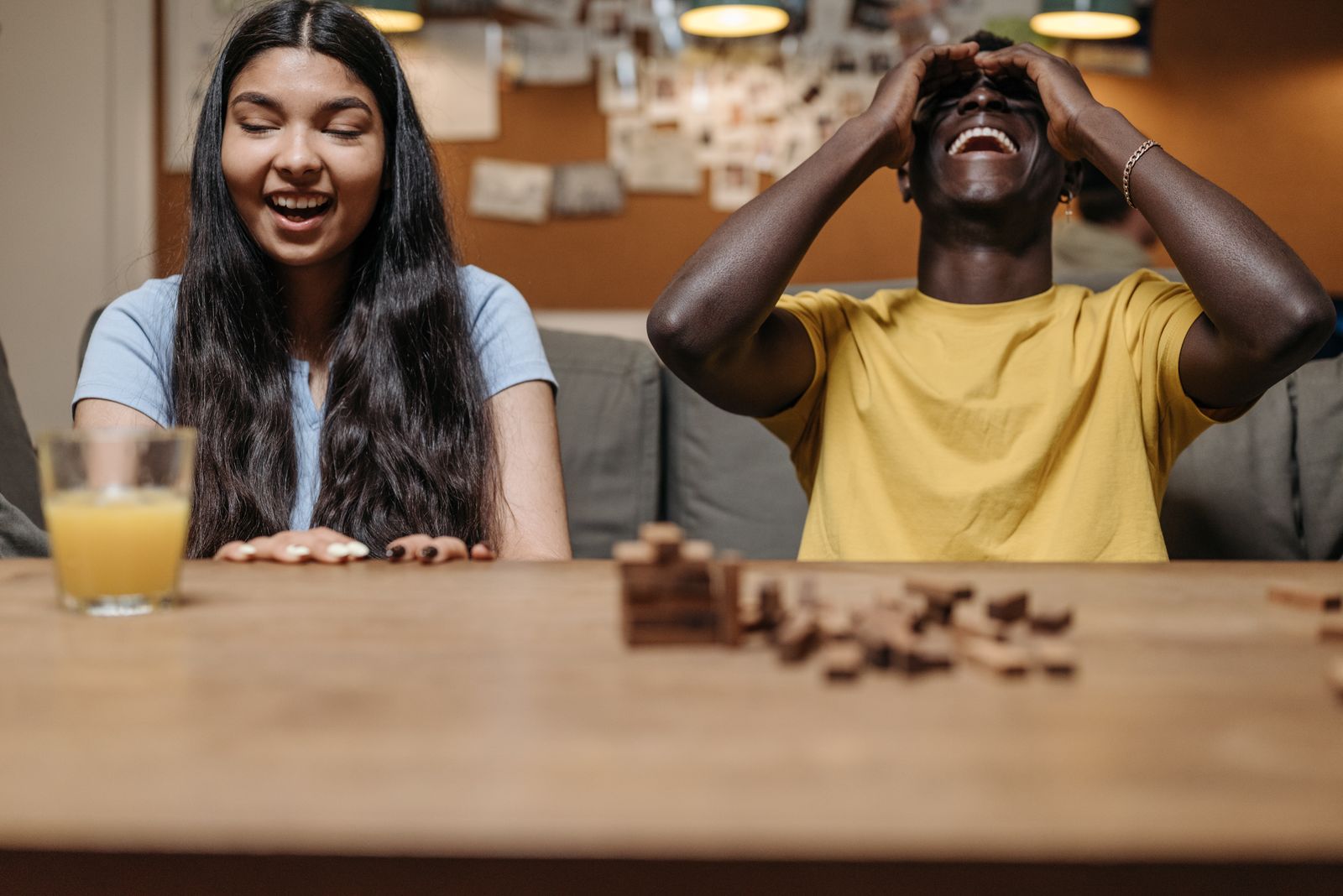 A friend reacting with laughter over a collapsed wooden block tower game