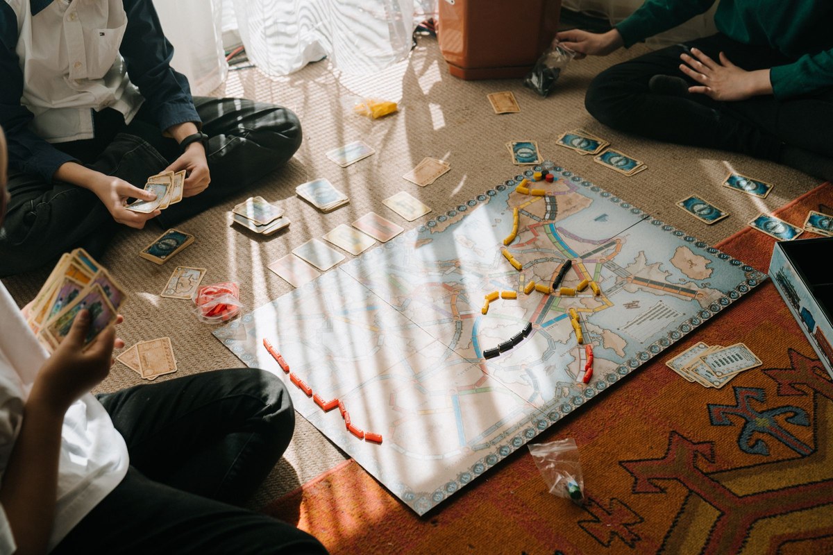 Kids playing a map-and-token strategy board game spread across the floor