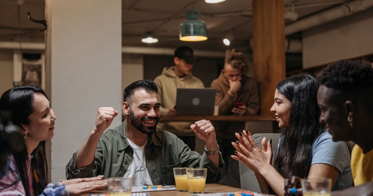 A group of adult friends celebrating over a colorful tabletop game