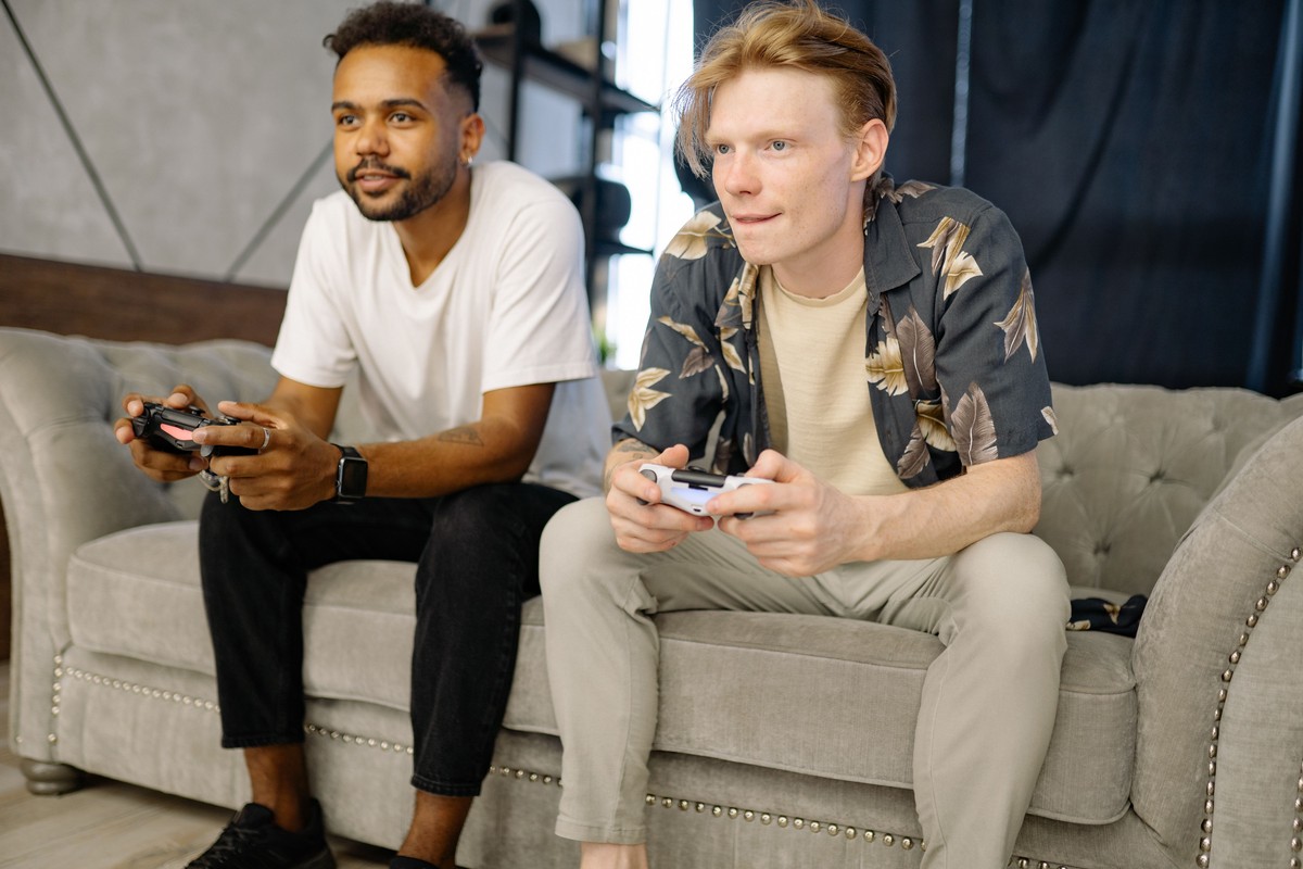 Two friends on a sofa playing a video game with controllers