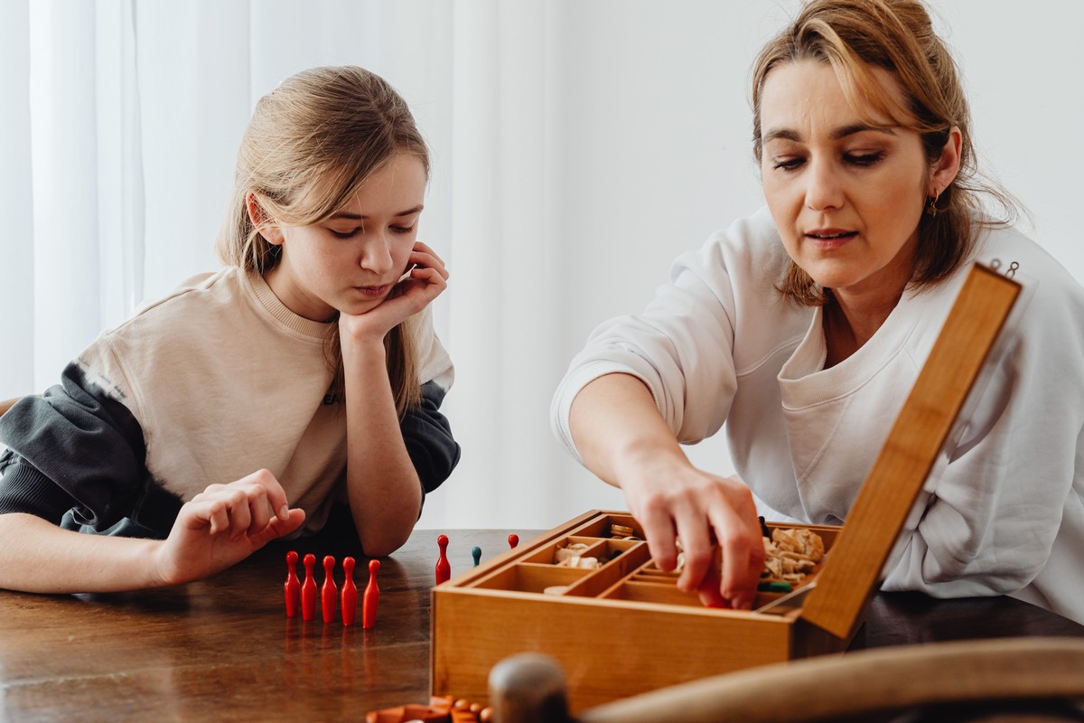 A mother and daughter sorting pieces from a wooden board game box